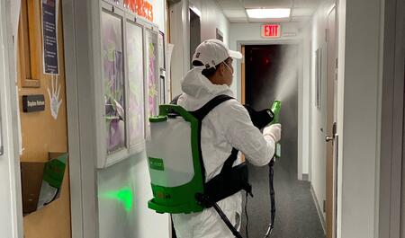 Man in a coveralls spraying sanitizer